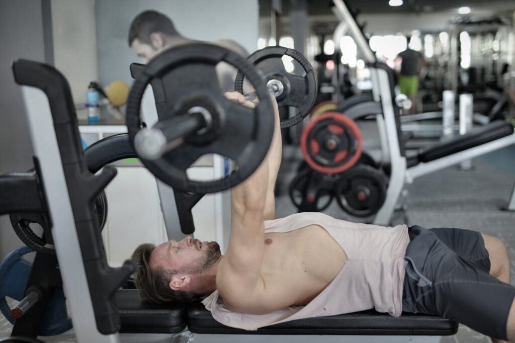 Strong sportsman doing bench press during workout in modern gym